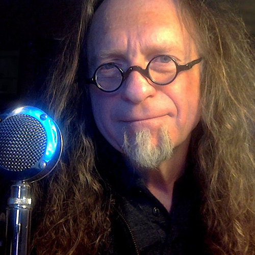 Bryan Konefsky in circle-framed glasses, with a vintage microphone