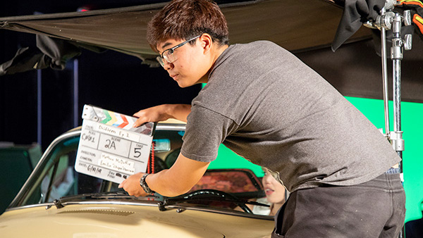 A student operates a film slate