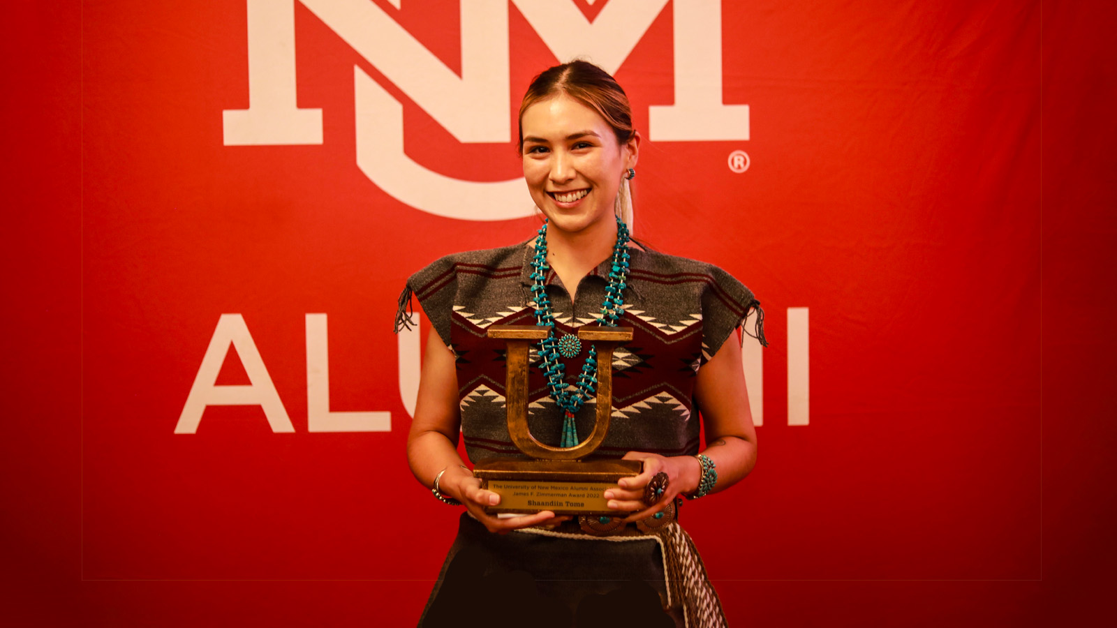 Shaandiin Tome smiling holding UNM Alumni award